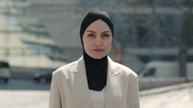 Başörtüsü ve resmi giysiler içinde gülümseyen kadın portresi