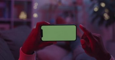 Elinde yeşil ekranlı cep telefonu olan bir adam.