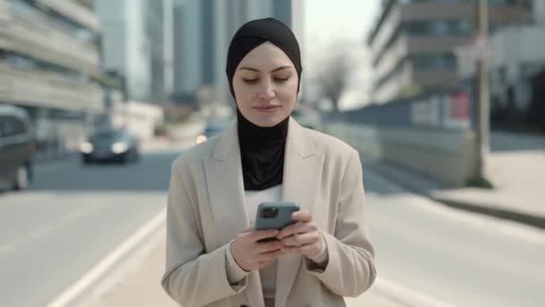 Приятная женщина в хиджабе со смартфоном на улице — стоковое видео