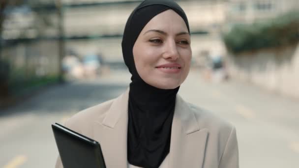 Žena v hidžábu chůze venku s podložkou v ruce