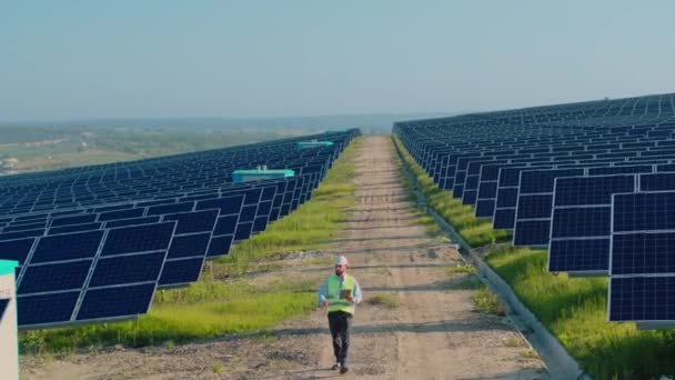 Ingeniero verificando paneles fotovoltaicos mientras camina sobre el terreno — Vídeo de stock