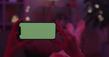 Elinde akıllı telefon ve yeşil ekran modeli olan bir kadın.