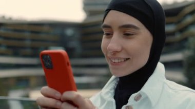 Türbanlı kadın internet üzerinden akıllı telefon kullanarak sohbet ediyor.