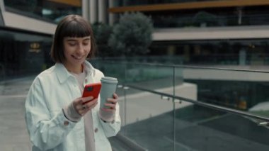 Alışveriş merkezinin yakınında akıllı telefon kullanan mutlu bir kadın.