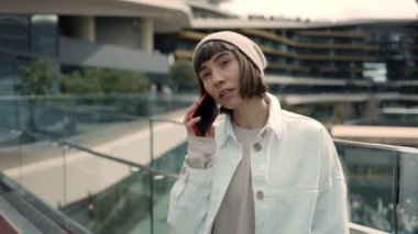 Alışveriş merkezinin yanında duran bir kadın cep telefonuyla konuşuyor.