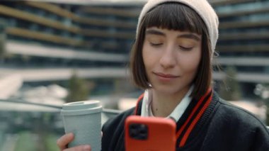 Cep telefonu kullanan ve alışveriş merkezinde kahve içen bir kadın.