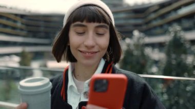 Kahve içen ve alışveriş merkezinde cep telefonu kullanan bir kadın.