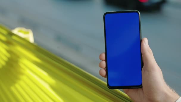 Крупним планом чоловіча рука тримає смартфон з синім екраном — стокове відео