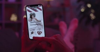 Lviv, Ukrayna - 05 Şubat 2021: Akıllı telefon tutan ve Asos uygulaması kullanan kadınlara yakın çekim