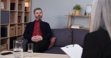 Olgun sakallı adam seansta kadın psikologla konuşuyor. Kadın terapist notlar alırken erkek yakışıklı konuşuyor. İnsanların sorunları, akıl sağlığı kavramı.