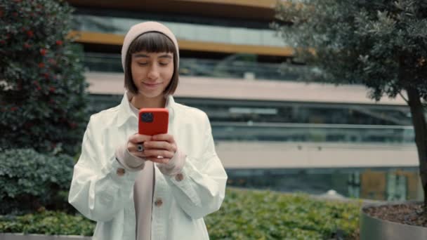 Mutlu kadın sokakta duruyor ve cep telefonu kullanıyor. — Stok video