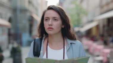 Bilinmeyen bir şehirde yürürken kağıt harita kullanan kadın turist