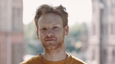 Açık havada poz veren kızıl saçlı, gülümseyen adamın portresi.