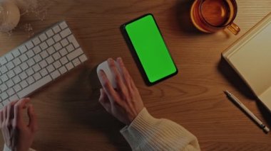 Klavyesi ve yeşil ekran telefonu olan bir kadın masada oturuyor.