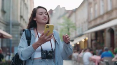 Sokakta dikilen bir kadın akıllı telefondan fotoğraf çekiyor.
