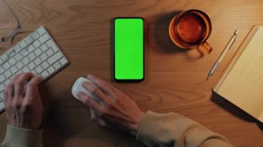 İş için cep telefonu, yeşil ekran ve klavye kullanan adam