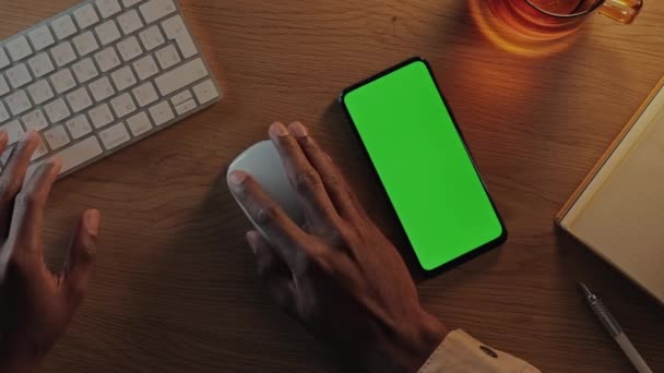 Afroamerykanin korzystający z telefonu komórkowego, klawiatury i myszy z zielonym ekranem — Wideo stockowe