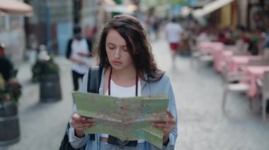 Kağıt haritalı güzel bir kadın eski şehirde yürüyor.