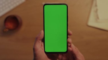 Yeşil ekranlı cep telefonunu tutan erkeklerin ellerini kapat