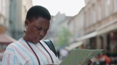 Kağıt haritalı Afrikalı Amerikalı kadın sokakta duruyor.