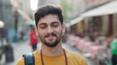 Sırt çantalı, dışarıda poz veren gülümseyen Hintli adamın portresi.