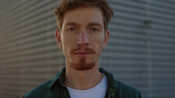 Hombre serio con el pelo rojo mirando a la cámara en la calle — Vídeos de Stock