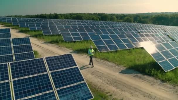 Techniker geht und untersucht Sonnenkollektoren auf Feld — Stockvideo