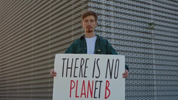 Redhead man med det finns ingen planet B banner på gatan — Stockvideo
