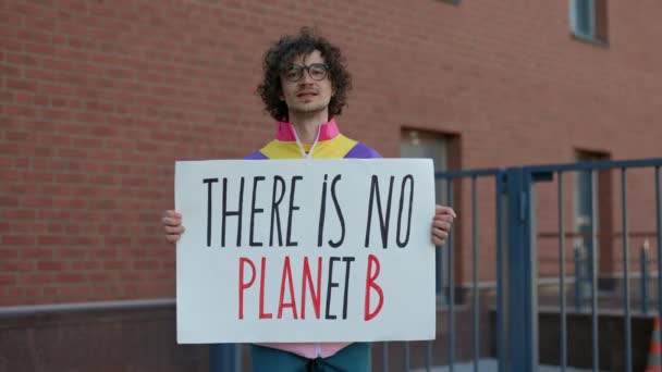 Молодой парень держит плакат с фразой "нет планеты Б" — стоковое видео