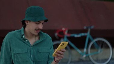 Panama şapkalı bir adam açık hava bisikletinden sonra cep telefonu kullanıyor.