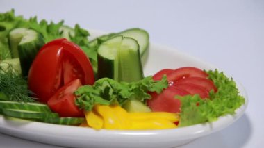 Beyaz arka plan üzerinde dönen bir tabakta sebze kesme