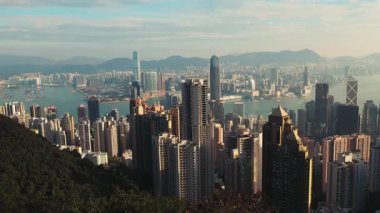 Skyline with various skyscrapers of Hong Kong downtown and calm river time-lapse. Business and financial center architecture under floating clouds in modern Asian megapolis