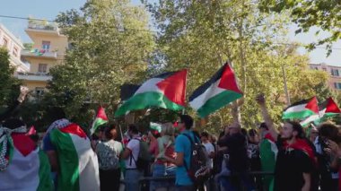Rome, Italy, 5.10.2025: Protesters wave Palestinian flags during a large political demonstration in the city streets surrounded by buildings and autumn trees.