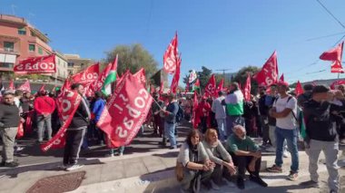 Rome, Italy, 5.10.2025: Demonstrators gather in the city streets with red union flags and banners during a political protest on a clear sunny day.