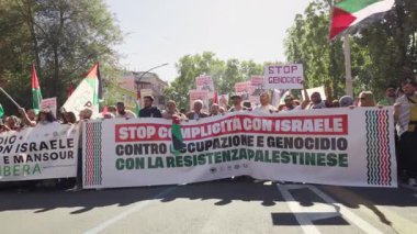 Rome, Italy, 5.10.2025: Protesters march in the city holding large banners and Palestinian flags with slogans against occupation and genocide during a political demonstration.