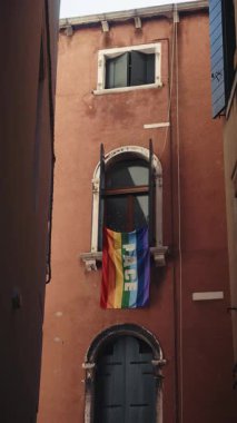 Üzerinde PACE kelimesi olan gökkuşağı bayrağı eski Venedik binasının kemerli camında asılı. Geleneksel festivalde LGBT topluluğunun simgesi. Ekleme desteği dikey çekim