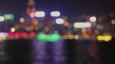 Rıhtımda çok renkli ışıklar ve sakin nehir odaklı gece manzarası. Parlak neon ışığı, turistleri Hong Kong 'un bulanık manzarasına çekiyor. Akşam Şehrinde Eğlence