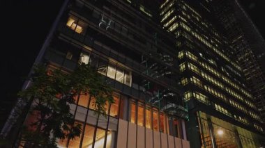 Hong Kong şehir merkezinde camları parlayan ticari ve apartman binaları. Modern şehir mimarisi, geceleri megapolis 'in ticari faaliyetlerini betimler.