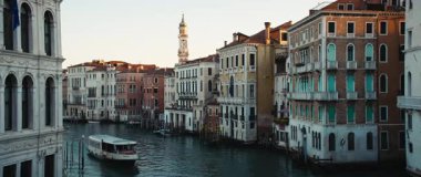 VENICE, İtalya - 05 Mart 2025: Günbatımında İtalya 'da tarihi apartman binaları arasında Grand Canal boyunca seyahat eden turist botu. Nehir tramvayı yolcuları Venedik limanındaki su yolunda