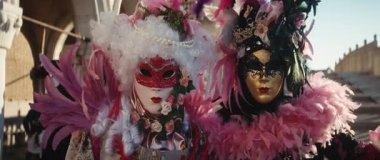 Venedik, İtalya - 05 Mart 2025: St Mark Meydanı 'nda çarpıcı maskeli karnaval kostümlü bayanların portresi. Kadınlar şehirde geleneksel maskeli balo kıyafetlerini parlak tüylerle oynarlar. Anamorfik lens