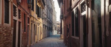 VENICE, ITALY - MARCH 05 2025: Narrow paved street with old apartment buildings on sides in Venetian district. Place with medieval spirit attracts tourist on vacation