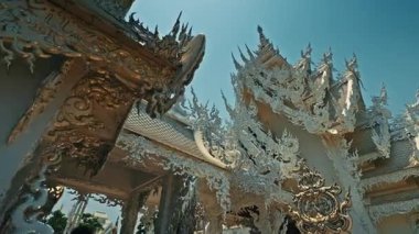 CHIANG RAI, THAILAND - 04 Eylül 2025: Tapınak binası parlak güneş ışığı altındaki altın süslemelerle muhteşem bir şekilde parlıyor. Altın süsler eşsiz zarafet ve ihtişam ile tapınağı kaplıyor.