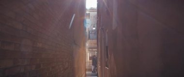 Venedik, İtalya - 05: 2025 Mart 'ta eski binaların duvarları arasındaki dar geçitten Venedik bölgesindeki işlek caddeye geçiyoruz. Antik kentin eşsiz ortaçağ mimari simgeleri