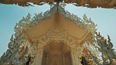 CHIANG RAI, THAILAND - 04 Eylül 2025: Beyaz Tapınak 'taki yapı duvarları karmaşık oymalı altın desenlerle parıldıyor. Şaşırtıcı altın süsler kutsal mimariye zarafet ve ihtişam katar.