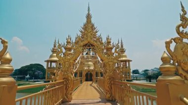 CHIANG RAI, THAILAND - Eylül 04 2025: Beyaz Tapınağa giriş köprüsü Budist kültürünün manevi anlamlarını simgeleyen ayrıntılı heykellerle süslenmiş. Suyla çevrili bir tapınak.