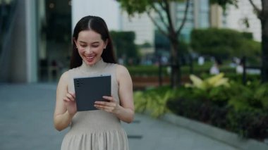 Güzel Asyalı kadın portresi şehir caddesinde yürürken sosyal medyayı dijital tablet üzerinde kaydırıyor. Koreli kadın finans bölgesinde gezerken mobil cihaz kullanıyor. Siber teknoloji