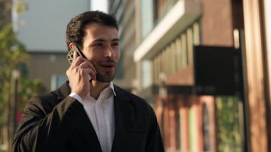 Pozitif İspanyol menajerin portresi ofis dışında cep telefonuyla konuşuyor. Resmi giyinmiş Latin işadamı, şehir merkezindeki akıllı telefon görüşmeleriyle müşterilerine danışıyor