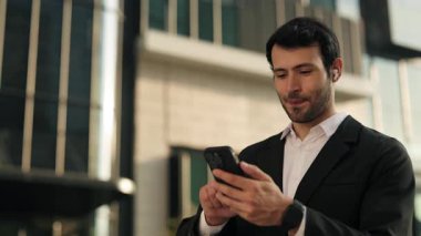 İspanyol girişimci portresi, ofis binasının dışındaki akıllı telefondan görüntülü çağrıya katılıyor. Latin işadamı modern kentte iş arkadaşlarıyla görüntülü konuşma yaptı