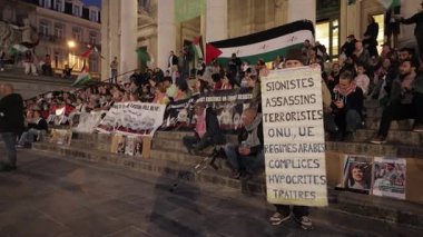 BRÜKSEL, BELGIUM - 27 Eylül 2025: Protestocular pankart ve Filistin bayraklarını akşam kasabasında ağır çekimde gösterilerde tutuyorlar. İnsanlar savaşa karşı uluslararası siyasete giriştiler