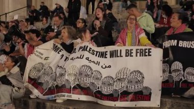 BRÜKSEL, BELGIUM - 27 Eylül 2025: Protestocular Özgür Filistin 'i yavaş çekimde sokak gösterilerinde büyük bir pankartla gösterdiler. Aktivistler gece kentinde savaşı protesto ediyorlar